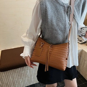 Minimalist brown woven bucket shoulder bag with sleek tassels and thin leather strap