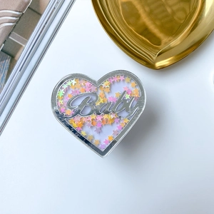 Detailansicht eines Herz-Handyhalters mit flüssigem Glitzer und Baby-Schriftzug