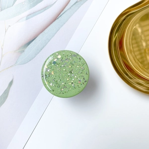 Macro shot of green glitter phone grip with star and moon sequins on white background
