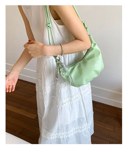 Detail of mint green crossbody bag featuring soft faux leather and silver metal charms