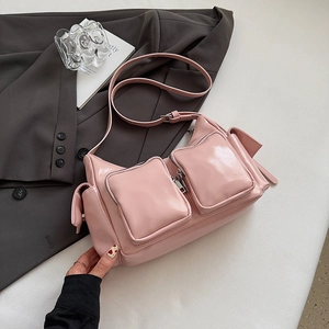 Detailed close-up of pink glossy patent leather handbag with dual front zipper pockets
