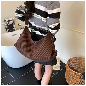 Detailed view of the dark brown houndstooth tote bag featuring a leather shoulder strap