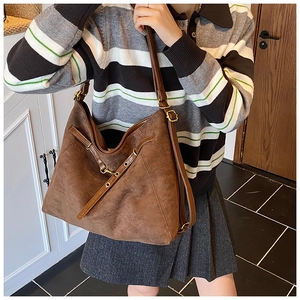 Détail d'un sac bandoulière en cuir mat marron foncé avec sangle sur le mannequin