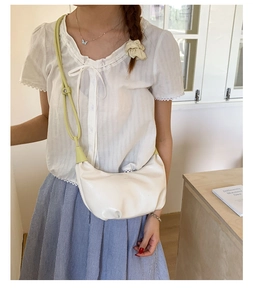 Detail view of the sleek white crescent bag with fresh green strap on a side-profile model