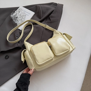 Close-up of multi-pocket glossy cream yellow shoulder bag on a dark blazer