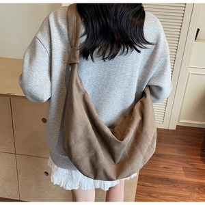 Detail of a brown canvas crossbody bag featuring a unique knotted shoulder strap design