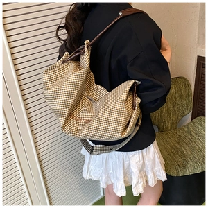 Detailed view of the large brown plaid tote bag with adjustable strap and logo print