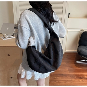 Detailed view of black canvas crescent bag with knotted strap on model in office setting