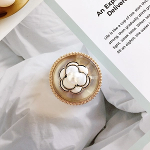 Close-up of vintage golden camellia pearl brooch on elegant white fabric background
