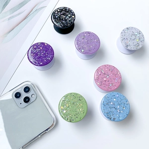 Close-up of glitter galaxy phone grip expanding on a minimalist white desk with plant