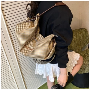 Detail of large check canvas tote bag with shoulder strap and embroidery shown on model