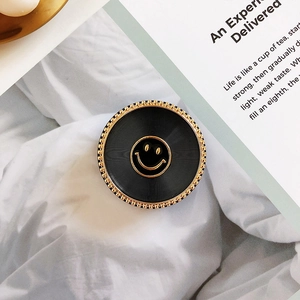 Macro view of black grip tok with golden smile face and metallic beads on white cloth
