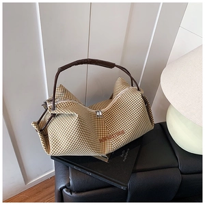 Detailed view of checkered canvas bag with leather handle and Monos Studio embroidery