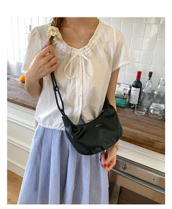 Detail shot of black crescent shoulder bag with adjustable strap in casual kitchen setting