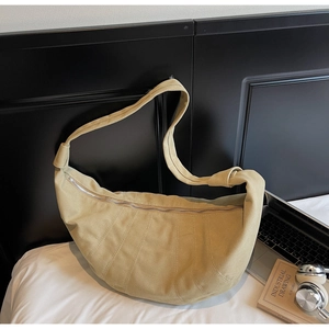 Detail of minimalist beige canvas crescent bag with curved stitching and metal zipper