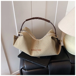 Close-up of brown gingham hobo bag with leather handle on a stack of books