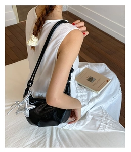 Close-up of black glossy dumpling bag with silver star pendant and fashion text print