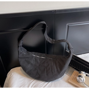Detailed close-up of dark grey crescent canvas bag with curved quilted stitching
