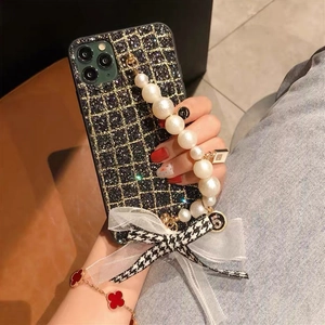 Detail of glitter checkered iPhone case with pearl bracelet and houndstooth bow charm