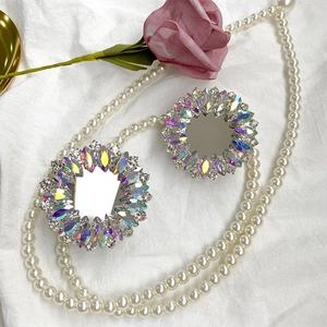 Foldable mirror phone stand with luxurious rhinestone petal design on white textured fabric