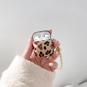 Coque AirPods léopard avec bracelet en perles tenue sur un pull en maille douce