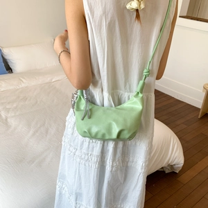 Pistachio green crescent crossbody dumpling bag with pleated detail and knot strap
