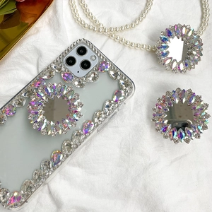Close-up of luxury rhinestone phone case with foldable mirror sockets on white fabric