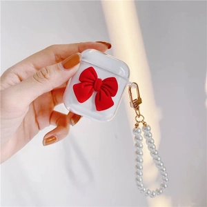 Clear AirPods case with large red velvet bow and pearl hand strap chain detail