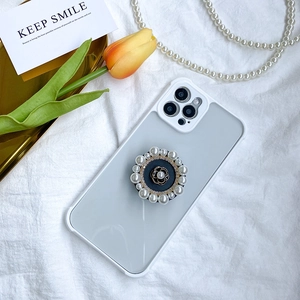 Detail of camellia flower phone grip with pearls and rhinestones on a white iPhone case