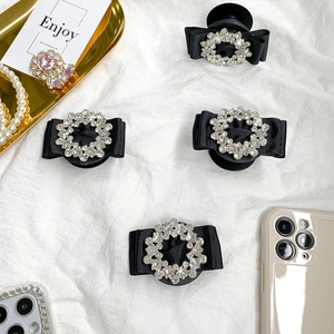 Close-up of luxury rhinestone bow phone socket holder on a marble and pearl surface