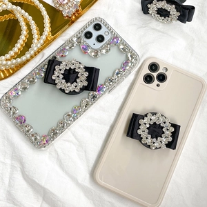 Close-up of luxury rhinestone bow phone grip on transparent and cream phone cases