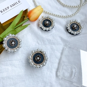 Black camellia flower phone grip with pearls and rhinestones on white fabric