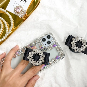 Detail of luxury rhinestone phone case with creative black ribbon bow collapsible stand