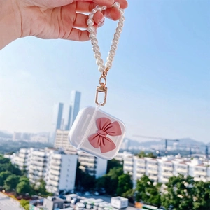 Clear TPU AirPods case featuring a pink matte bow and white pearl beaded strap