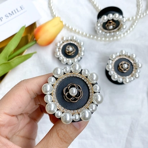 Foldable camellia phone stand with white pearls and rhinestones on a black base
