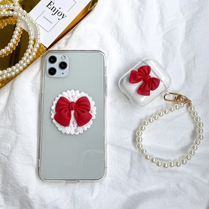 Clear AirPods case featuring a delicate red bow and decorative white pearl beaded lanyard