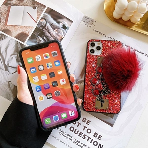 Detail of red glitter phone case with luxury faux fur pompom and ruby charm chain