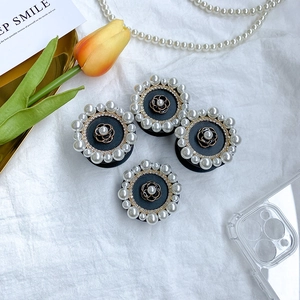 Detail of camellia flower phone socket with rhinestones and white pearls on white fabric