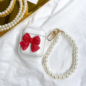 Detail of transparent AirPods case with 3D red ribbon bow and white pearl wrist strap