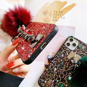 Detail of glitter phone case with large faux fur pompom and decorative jewel metal chain