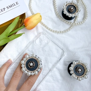 Detail of camellia flower phone socket with pearls and rhinestones on a white background