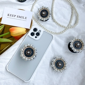 Detail of camellia flower phone grip with pearls and rhinestones on a white case