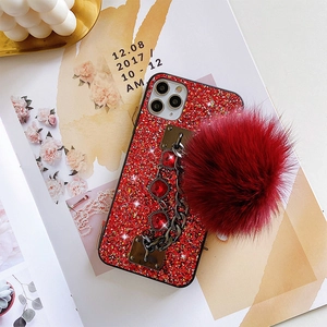 Detail of red glitter phone case with luxury gem chain and soft faux fur pompom charm