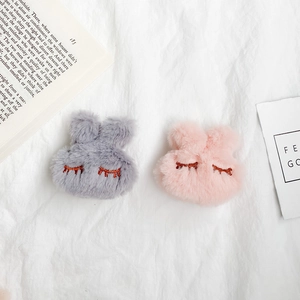 Close-up of cute plush bunny phone grips in grey and pink colors with soft fur texture