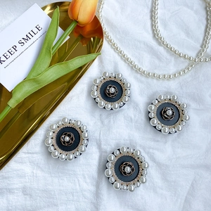 Close-up of four floral phone grips with pearls and rhinestones on white fabric