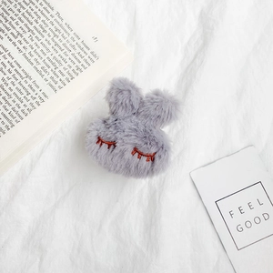 Close-up of grey plush rabbit phone stand with soft texture and embroidered details