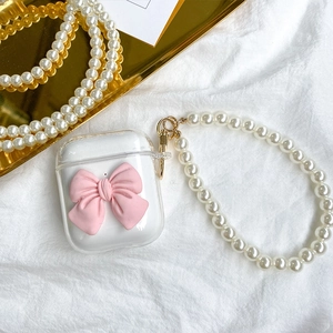 Detailed view of clear TPU AirPods case with a 3D pink bow and white pearl lanyard strap