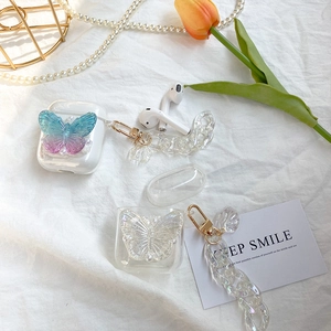 Colorful butterfly AirPods case with acrylic chain and pearl accents on white fabric