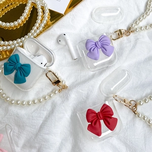 Detail view of clear TPU AirPods case featuring a colorful bow and elegant pearl strap