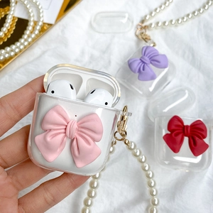 Close-up of clear TPU AirPods case featuring 3D bow decor and a white pearl handle strap